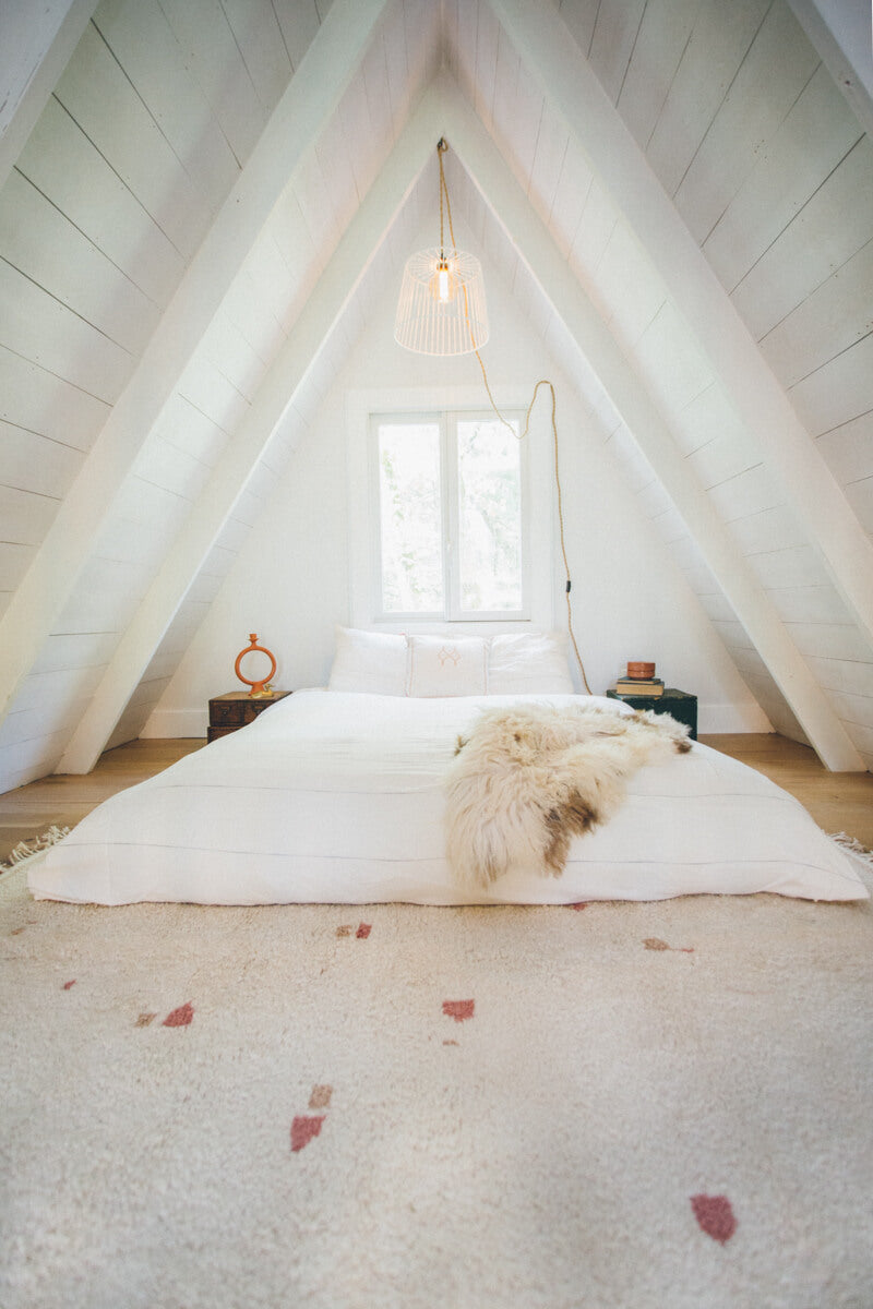 Loft A-frame bedroom featuring Rose and Champagne Blush PEBBLE Customizable Moroccan Wool Rug at foot of bed