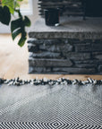 close up of Black + White Made-to-order Zanafi Moroccan Wool Rug at stone fireplace