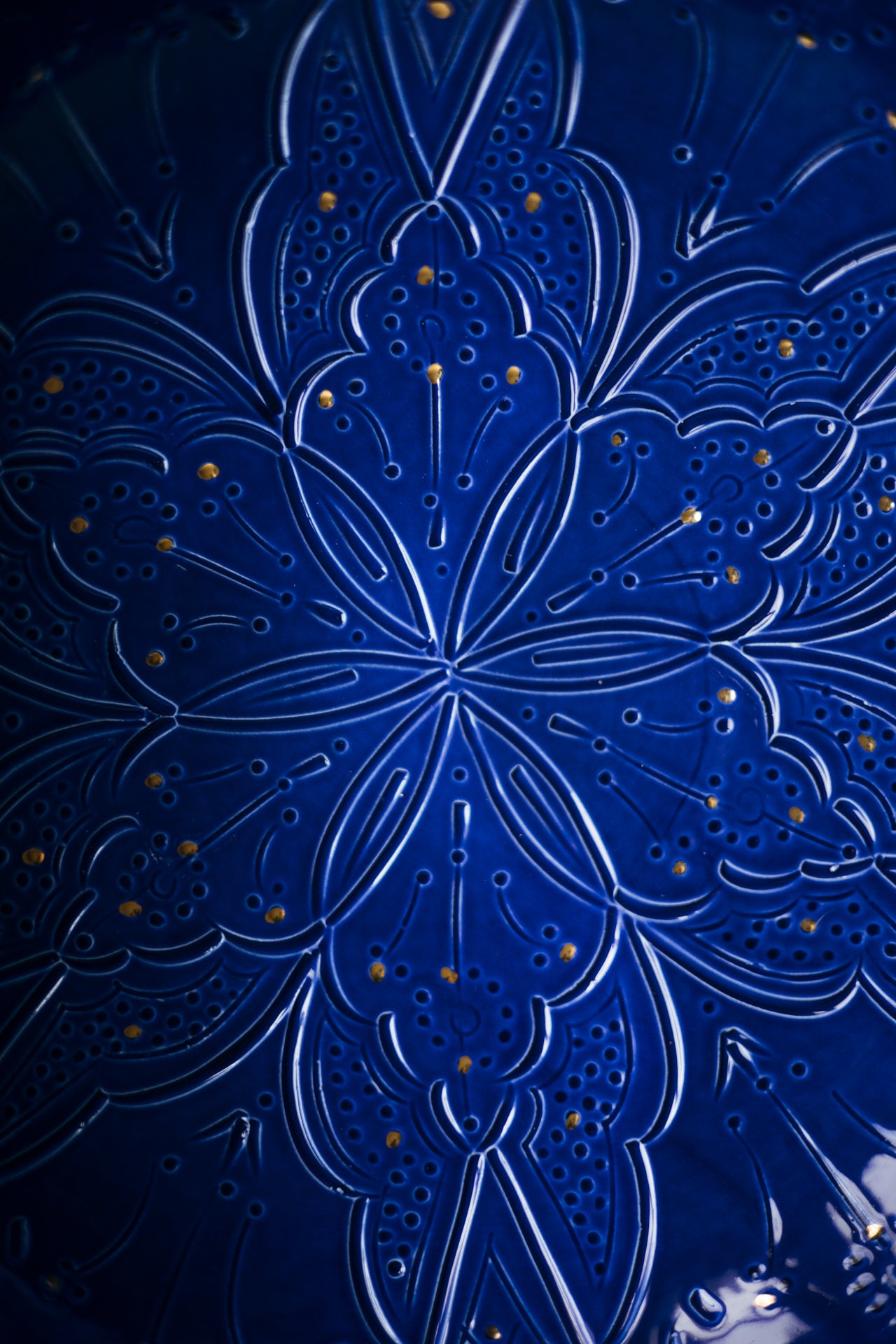Close-up of a blue decorative glass surface with intricate embossed Moroccan patterns