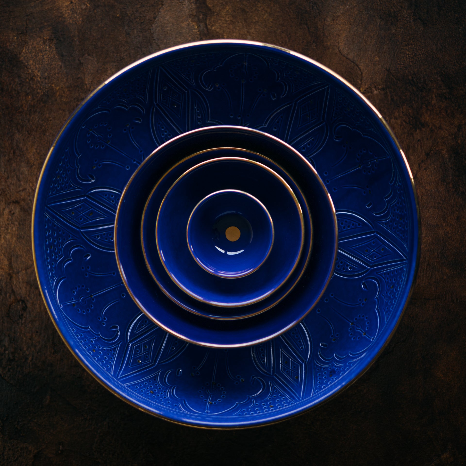Stack of blue Chabi Chic ceramic plates with intricate patterns on a dark background