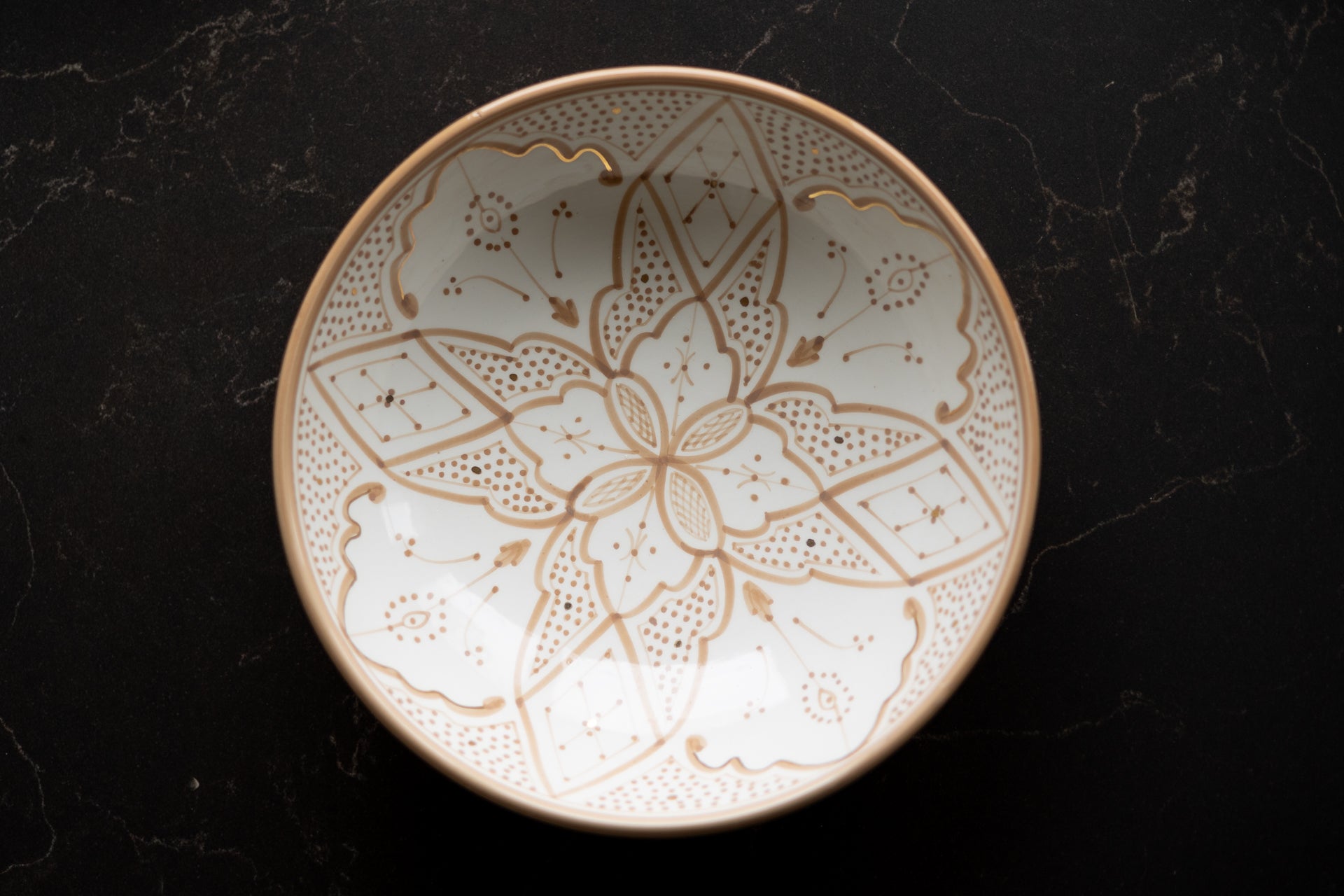 Decorative ceramic bowl with traditional Moroccan Zwak patterns on a dark surface