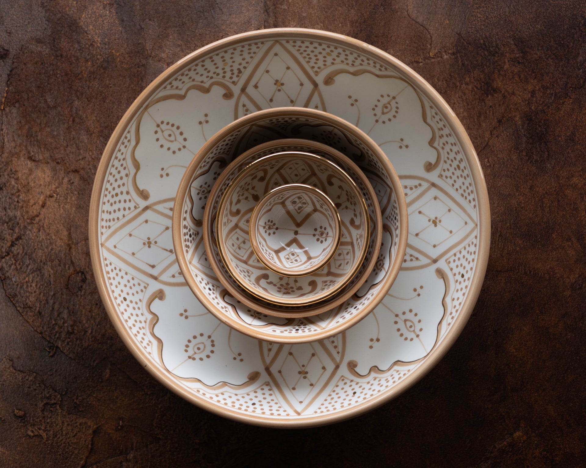 Stack of ceramic bowls with decorative Moroccan patterns on a textured surface