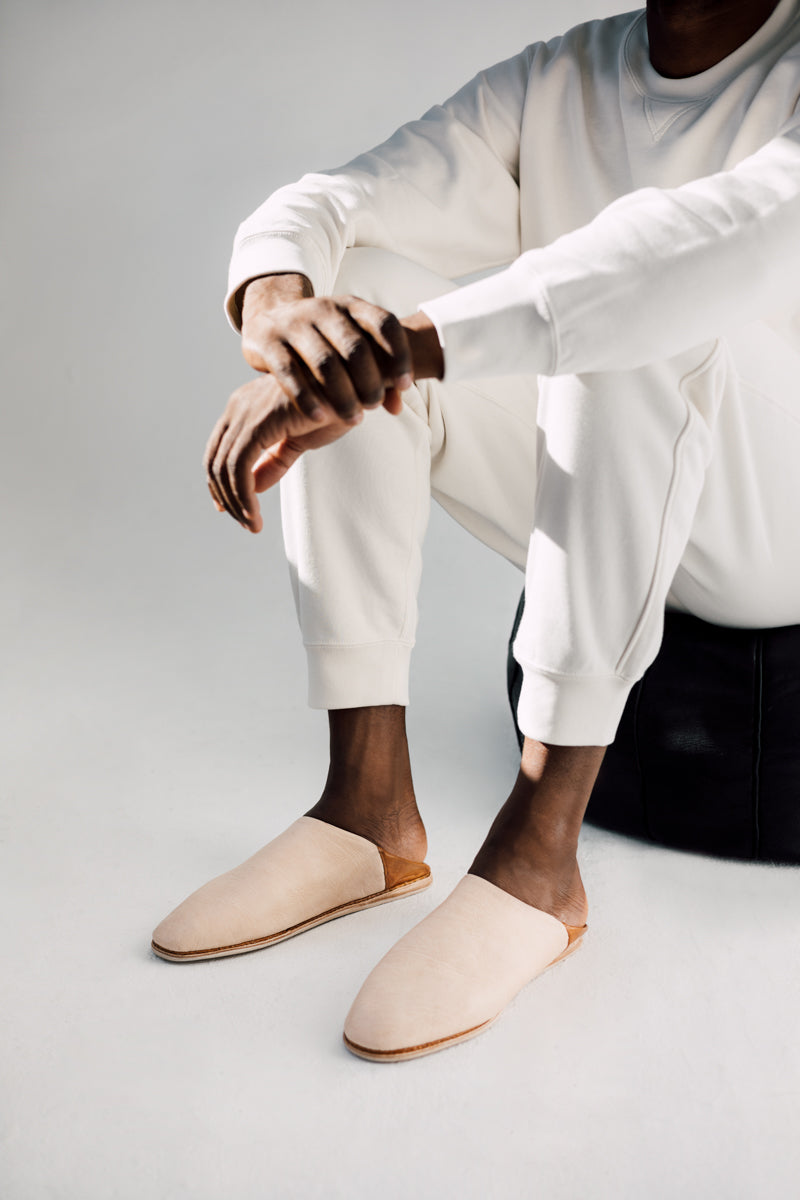 Close up man wearing Ouive Unisex House Shoe in Light Natural undyed leather with Tan brown heel