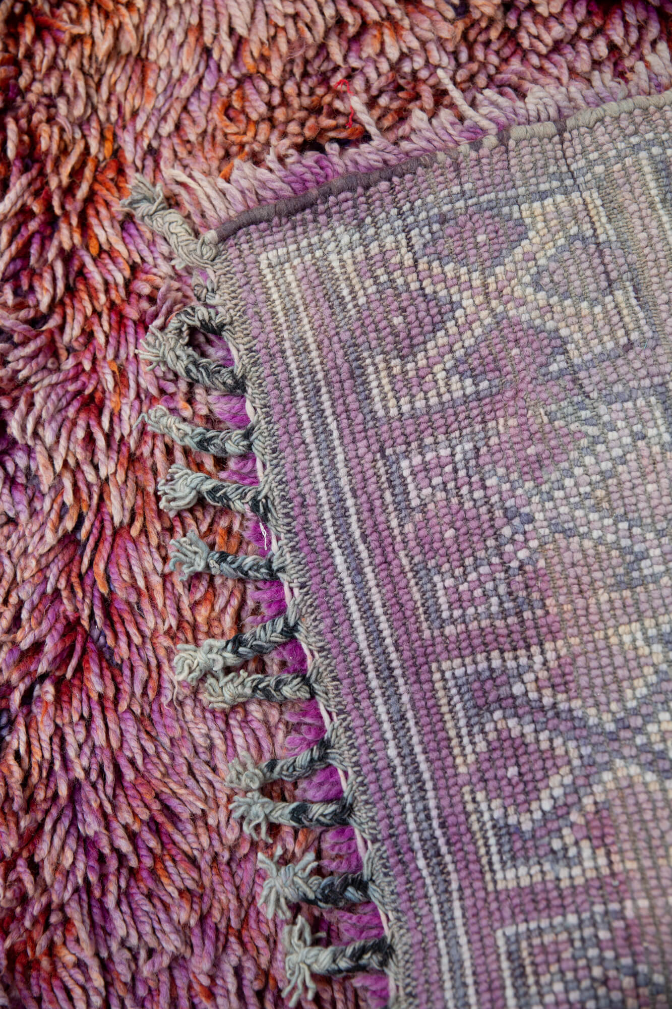 Vintage multicolr shag Moroccan wool rug showing corner flipped over to see backside knots