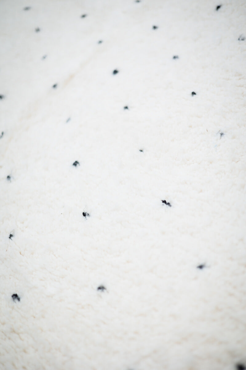 close up of white natural wool pile with black dots