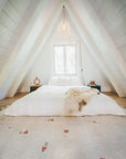 Loft A-frame bedroom featuring Rose and Champagne Blush PEBBLE Customizable Moroccan Wool Rug at foot of bed