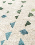 Close up diagonal detail photo of Ouive Jardin Green, Aqua and white Moroccan wool rug