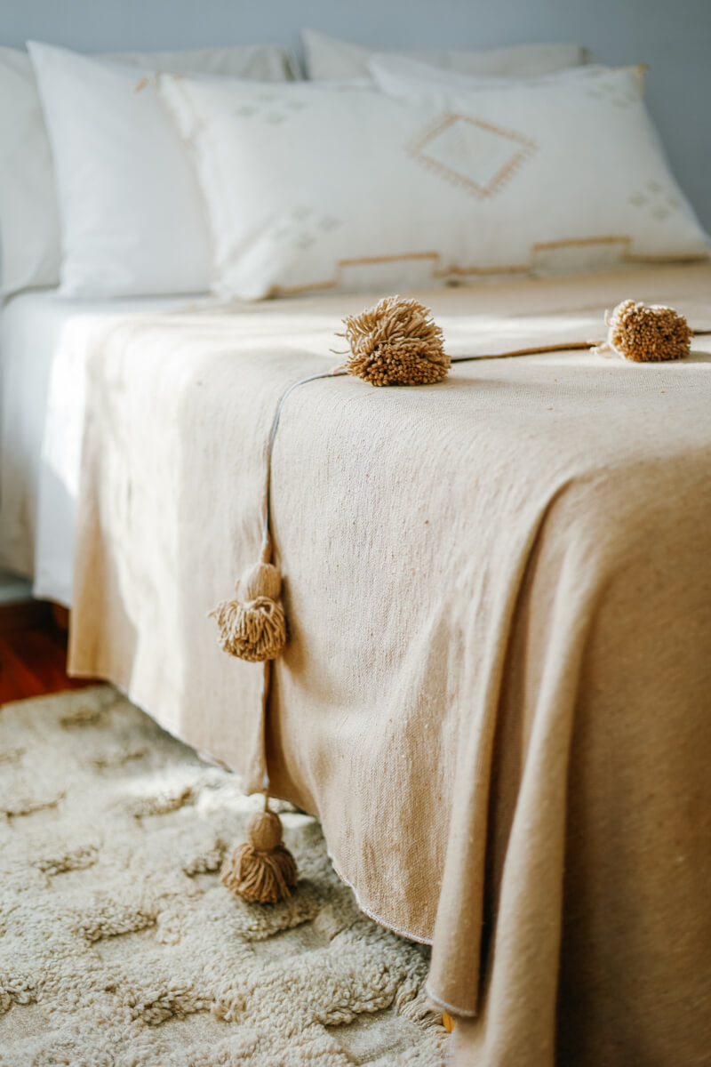 Close up of Pom Pom on Beige Cotton Moroccan Blanket