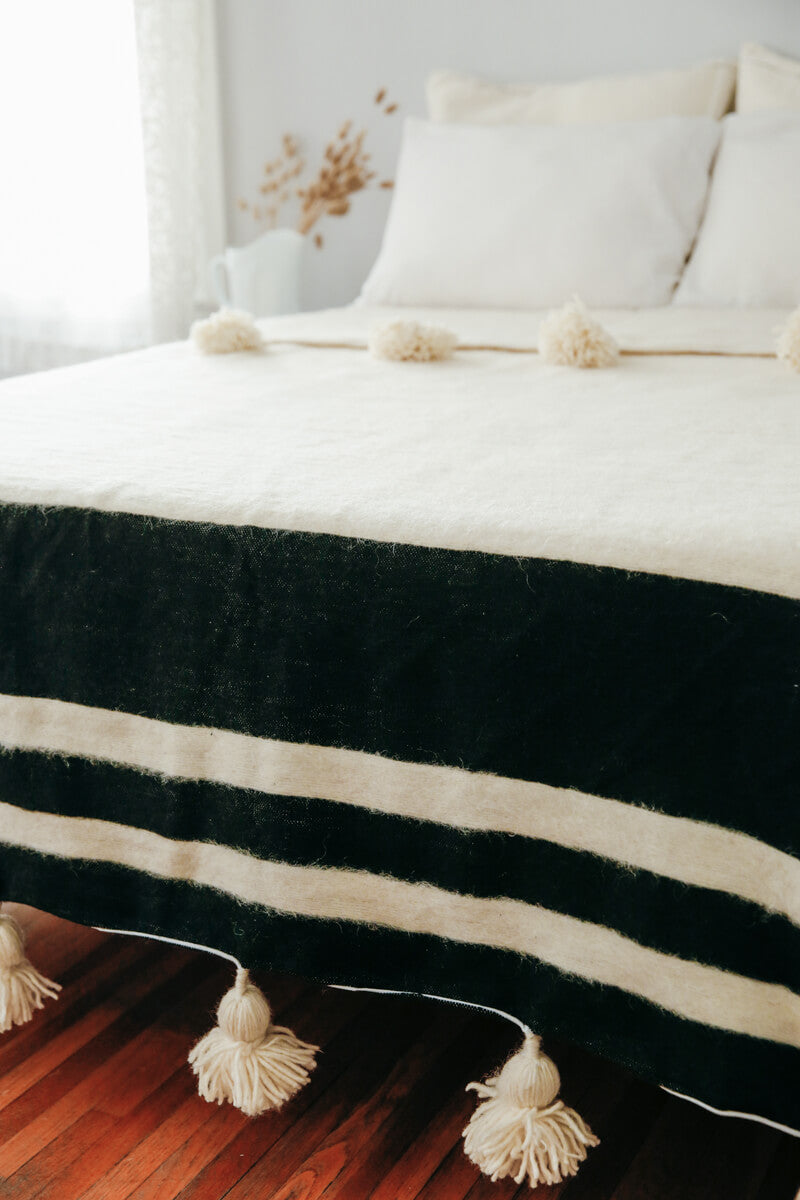 Moroccan Pom Pom Wool Blanket - Natural White with Black Stripes styled on bed