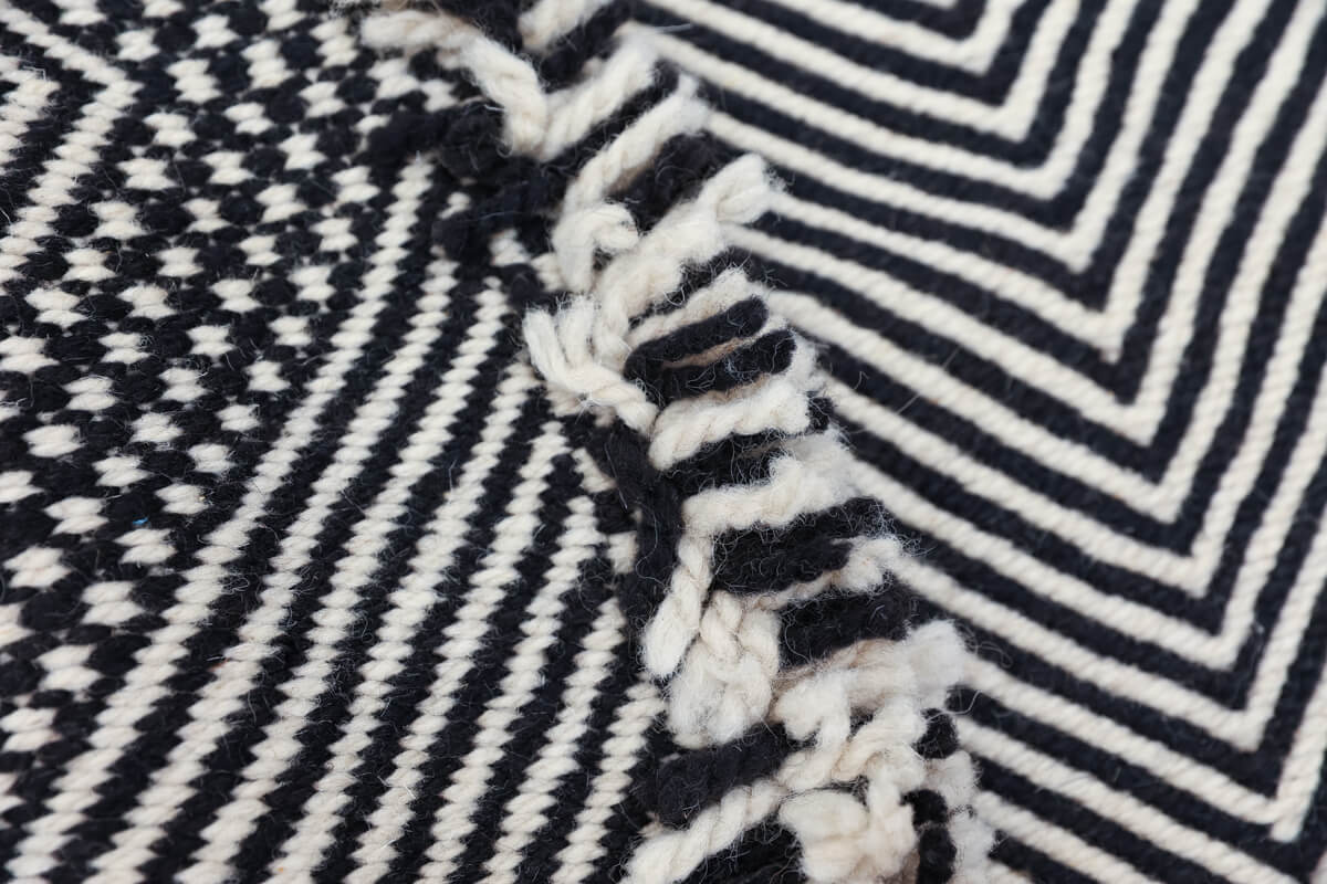 Close up of side fringe of Black + White Made-to-order Zanafi Moroccan Wool Rug