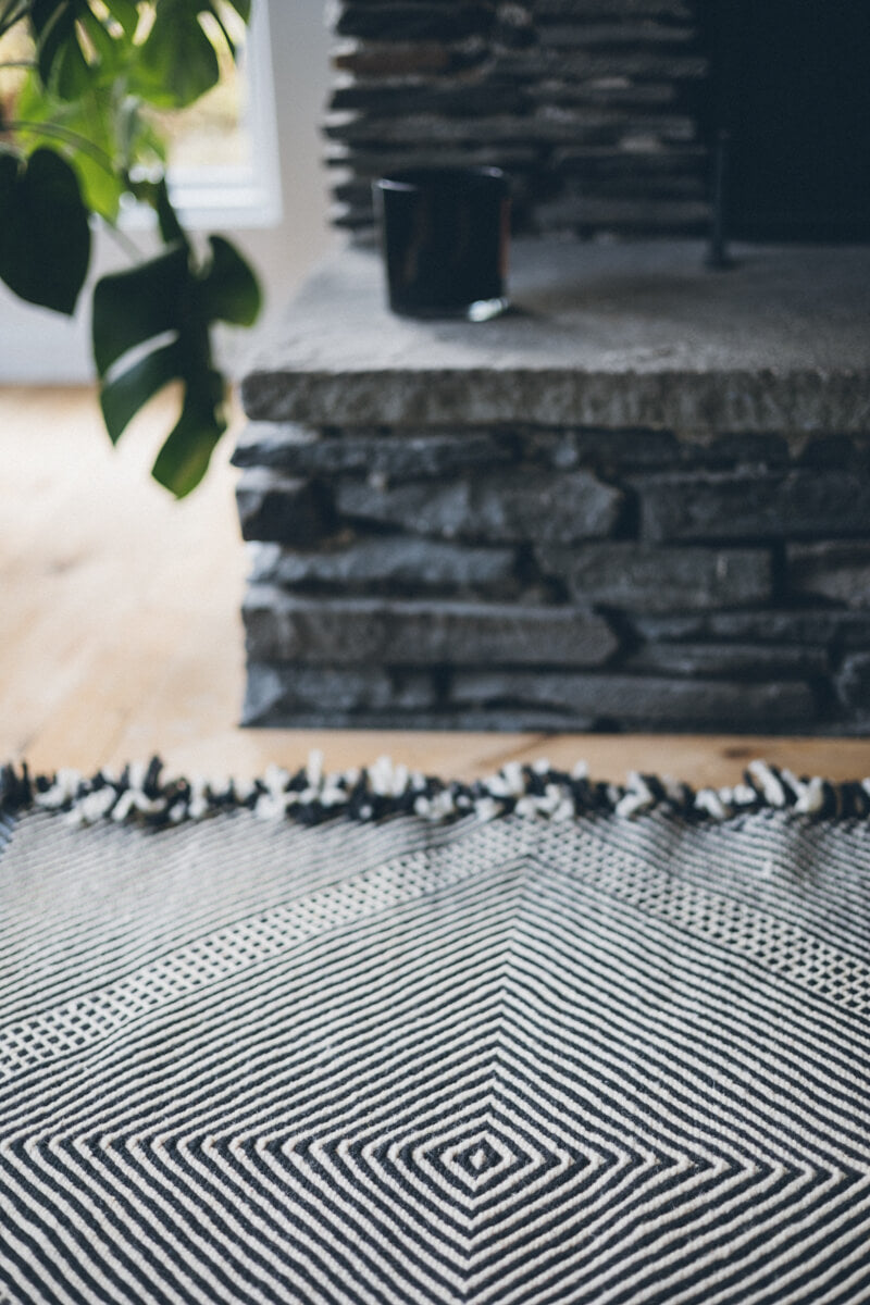 close up of Black + White Made-to-order Zanafi Moroccan Wool Rug at stone fireplace